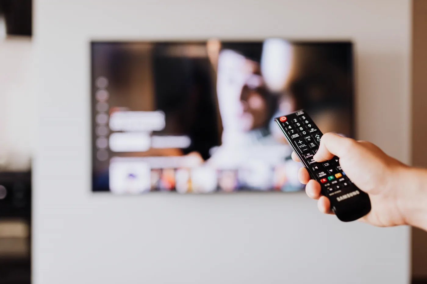 Mână care folosește telecomanda televizorului